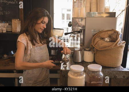 Barista mit einem Stampfer zu drücken Sie gemahlenen Kaffee in eine portafilter Stockfoto