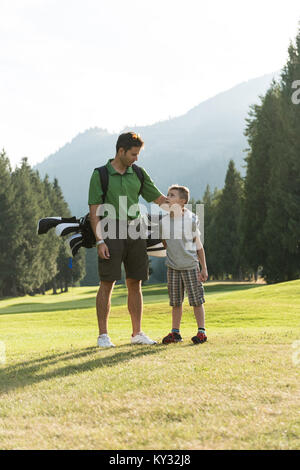 Vater und Sohn mit Golf Bag mit einander interagieren Stockfoto