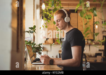 Man Musik hören über Kopfhörer während Mobiltelefon Stockfoto