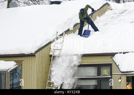 Ein Mann clearing Schnee vom Dach eines Hauses, Quebec City im Winter Stockfoto