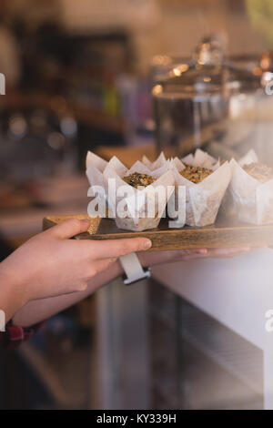 Nahaufnahme der Kellnerin holding Muffins in Fach Stockfoto