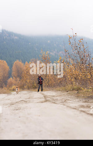 Mann und sein Hund spielen auf leeren Pfad Stockfoto