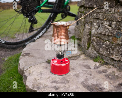 Die türkischen Kaffee mit einem traditionellen Kupfer ibrik auf ein Gas Campingkocher auf der Long Mynd im Shropshire Hills, Großbritannien Stockfoto