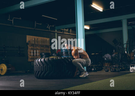 Muskulöse mann Training mit schweren Reifen Stockfoto