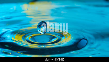 Wassertropfen spritzen in einem Glas blau Stockfoto
