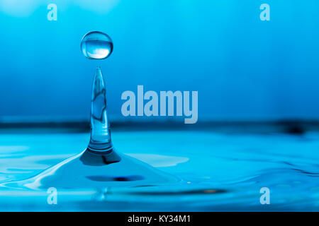 Wassertropfen spritzen in einem Glas blau Stockfoto
