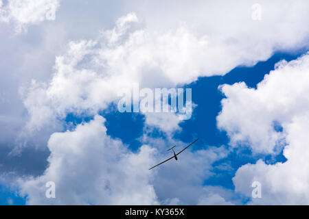 Ein Segelflugzeug fliegen in bleu Sky mit großen weißen Wolken. Der Schirm ist ein Flugzeug, das hat keinen Motor Stockfoto