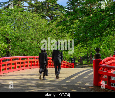 Ein paar wenige auf rote Brücke über den Burggraben der Burg Hirosaki in Aomori, Japan. Stockfoto