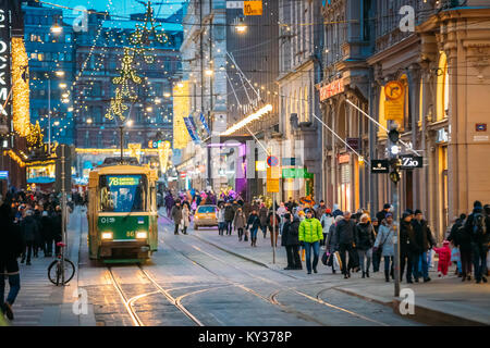 Helsinki, Finnland - 11. Dezember 2016: Straßenbahn fährt von der Haltestelle Aleksanterinkatu Straße. Straße mit Eisenbahn in Kluuvi erhalten Bezirk am Abend oder in der Nacht Stockfoto