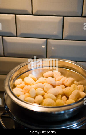 Makroaufnahme der Ungekochte Gnocchi in Edelstahl Schüssel in Küche mit Metro Style Kacheln im Hintergrund Stockfoto