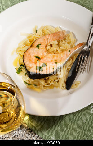 Gegrilltes Lachssteak mit Tagliatelle auf einer Platte und einem Glas Weißwein Stockfoto