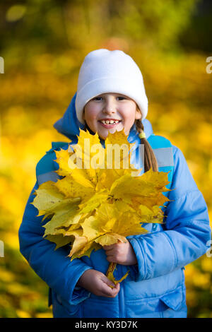 Sieben Jahre Mädchen hält Ahorn Blätter Strauß Stockfoto