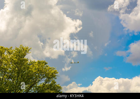 Ein Segelflugzeug fliegen in bleu Sky mit großen weißen Wolken. Der Schirm ist ein Flugzeug, das hat keinen Motor Stockfoto