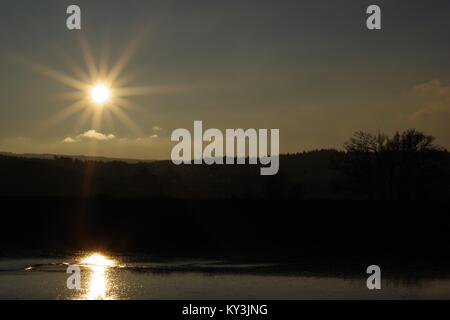 Sonnenuntergang über dem bewaldeten Winter Farmland der Powderham Immobilien, Silhouetting Bäume in der Dämmerung. Vom Rasen Hotel, Exe Estuary, Devon, Großbritannien. Stockfoto