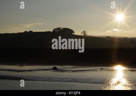 Sonnenuntergang über dem bewaldeten Winter Farmland der Powderham Immobilien, Silhouetting Bäume in der Dämmerung. Vom Rasen Hotel, Exe Estuary, Devon, Großbritannien. Stockfoto