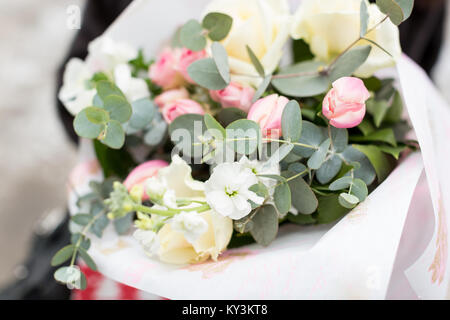 Blumenschmuck, Hochzeit, überraschung Konzept. In der Nähe von Bouquet verpackt in Weiß craft Papier, es wird gesammelt von extrem schöne und zarte f Stockfoto