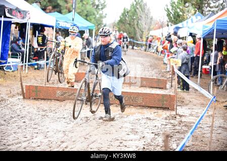 Cyclocross racers Verfahren vielfältige Gelände, über Hindernisse, in regnerischen Bedingungen während in Halloween Kostüme im Oktober 2016 in Bend, Oregon gekleidet. Stockfoto