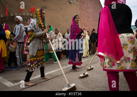 Sikhs Frauen in Leicester, England feierlich das Fegen der Weg während einer Bi - jährliche Prozession durch die Straßen der Stadt. Laut der Volkszählung von 2011 lebten 14.500 Menschen in der Sikh Glauben leben in Leicester, rund fünf Prozent der Bevölkerung. Die örtlichen Fußballverein, Leicester City, wurden am Rande des Seins überraschung Gewinner der Englischen Premier League in der Saison 2015-16. Stockfoto