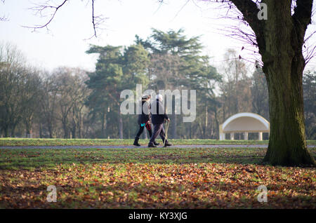Paar zu Fuß in Brinton Park, Kidderminster zu Fuß in Richtung Bandstand an einem kalten, nebligen Morgen im Dezember. UK Park. Stockfoto