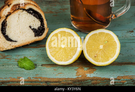 Zitrone und Tasse Tee mit Minze Blatt und Mohn Kuchen Stockfoto