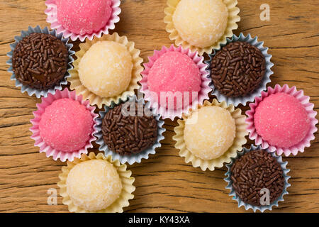 Brasilianische Spezialitäten: Brigadeiro, Beijinho und Bicho de Pe. Kindergeburtstag. Overhead von candy Ball auf rustikalen Holztisch. Stockfoto