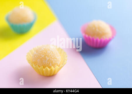 Beijinho ist ein handgefertigtes Candy aus Brasilien. Mit Kondensmilch und Kokosnuss. Kinder brithday party Süße. Verbreitung candy Kugeln auf bunten Tisch. D Stockfoto