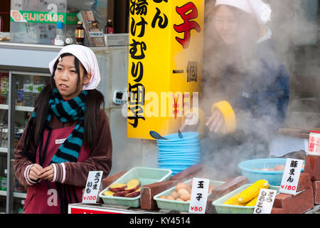 Beppu, Japan. Zwei junge Mädchen Kochen am freien Markt. Gekochte Eier, Mais und Kartoffeln ist beliebt fast food. Stockfoto