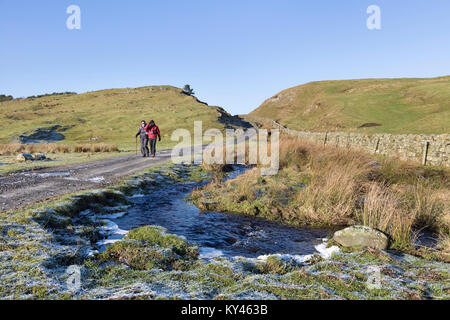 Hadrian's Wall: Wanderer an einem frostigen Winter beim Melken Lücke, in der Nähe der Crag Lough. Die Bradley Brennen können gesehen fließt neben dem Weg hier. Stockfoto