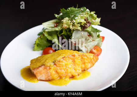 Filet vom Lachs Fisch und Käse auf einem Teller mit Salat, Rucola und Tomaten mit Sesam. Stockfoto
