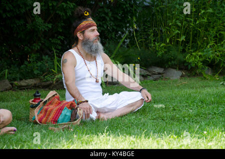 Mann sitzt im Schneidersitz in Gras beobachten, Leistung, Kasilof NY, USA Stockfoto