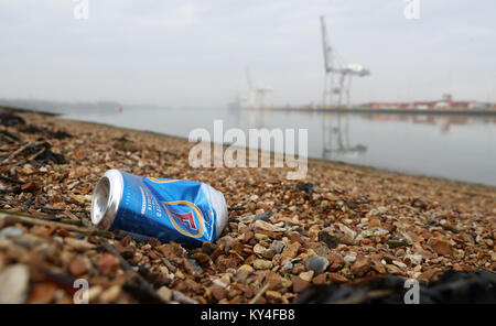 Eine weggeworfene fördert. Bier kann auf einen Kiesstrand gegenüber DP World Container Terminal in Southampton Stockfoto