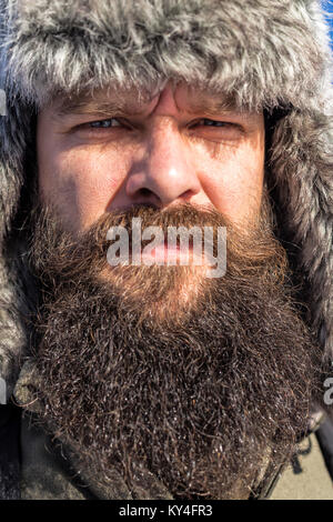 Closeup Portrait eines bärtigen jungen Mann mit pelzkappe Outdoor Stockfoto