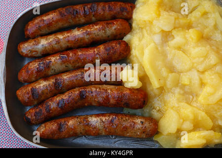 Close up Teil der gegrillten Nürnberger Bratwurst Bratwurst mit Beilage von Kartoffelsalat auf Metall Zinnteller, Erhöhte Ansicht von oben, direkt über Stockfoto