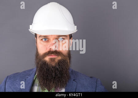 Junge Bartgeier Ingenieur mit weißen Helm über grauer Hintergrund Stockfoto