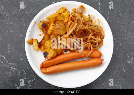 Nahaufnahme, Teil zwei brühwurst mit gerösteten Kartoffeln und gebratenen Zwiebeln auf weißen Platte über graue Tabelle, Erhöhte Ansicht von oben, direkt über Stockfoto