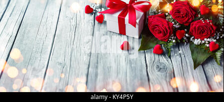 Valentines Card - Geschenkbox und Rosen auf Holztisch mit Beleuchtung Stockfoto
