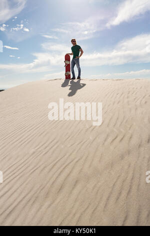 Mann mit Sandboard stehend in der Wüste Stockfoto