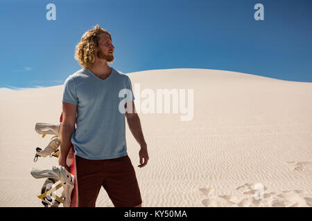 Mann mit Sandboard stehend in der Wüste Stockfoto