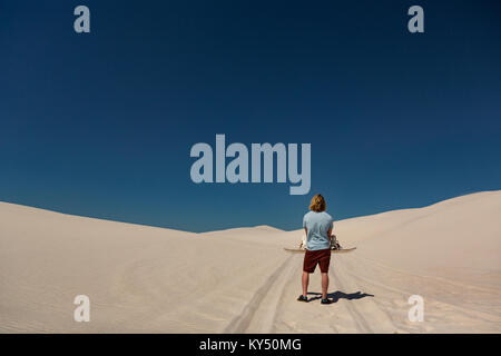 Mann mit Sandboard stehend in der Wüste Stockfoto