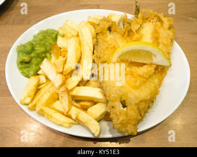 Eine Umhüllung von Scholle und Chips mit schönen Teig eine Scheibe Zitrone und Erbsenpüree, bereit zum Essen in ein Restaurant Stockfoto