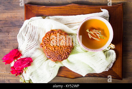 Chinesischen mooncake und Tee mit Rose auf Holz- Untertasse serviert. Stockfoto