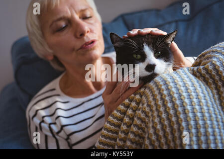 Ältere Frau sitzt auf dem Sofa und streichelt Ihre Katze zu Hause Stockfoto