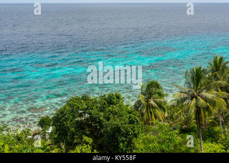 Erhöhten Insel Blick über Palmen und Küste Dschungel heraus zu einem seichten und ruhigen tropischen türkisfarbenen Meer an einem sonnigen Tag. Stockfoto