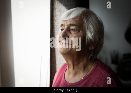 Ältere Frau stehen in der Nähe von Fenster Stockfoto