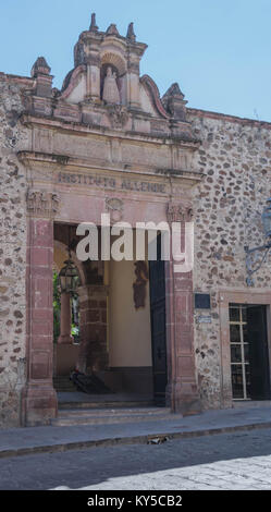 Vor Eingang des Instituto Allende, mit Steinmauer, steinernen Eingang, mit kunstvollen Schnitzereien und Straße mit Kopfsteinpflaster, in San Miguel de Allende Stockfoto