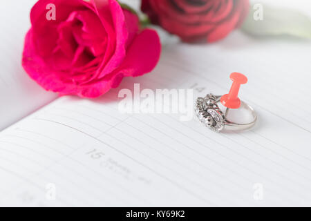 Diamantring auf Kalender Buch mit rosa Rose, Liebe und Valentinstag Konzept Stockfoto