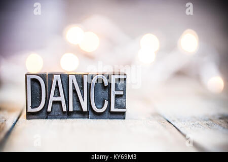 Das Wort Tanz in vintage Metall buchdruck Art auf einem bokeh Licht und Holz- Hintergrund geschrieben. Stockfoto