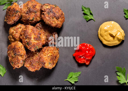 Schiefer Tafel mit hausgemachten frikadellen aus Schweinefleisch, Rindfleisch und Gemüse mit Tomatensauce und Senf hergestellt Stockfoto