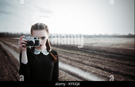 Ernsthafte junge Mädchen Fotografieren durch die alte Filmkamera. Outdoor Portrait im Feld Stockfoto