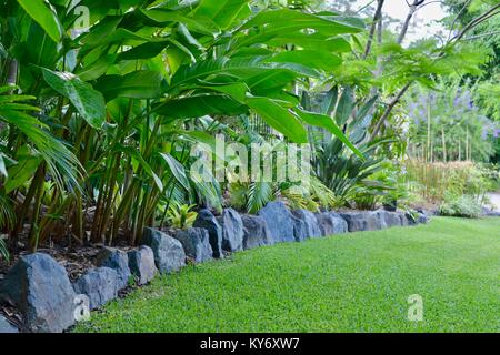 Große steinerne Grenze zwischen Rasen von einem Garten Bett, Sunshine Coast, Queensland, Australien Stockfoto